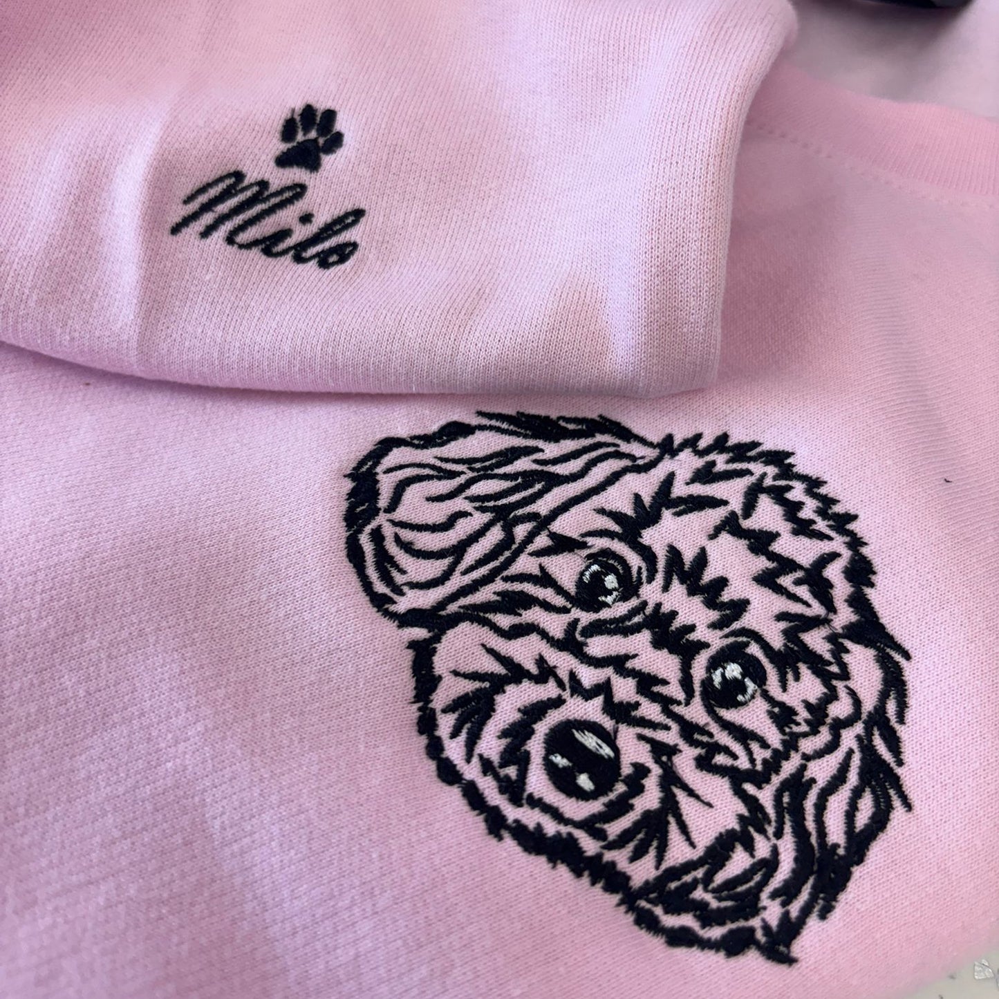 Pink sweatshirt with a black bear head design and 'Milo' embroidered on it.